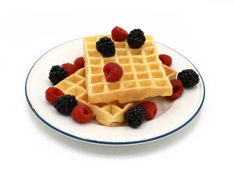  fresh belgian waffles with raspberrys and blackberries on a plate isolated on white background