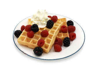  fresh belgian waffles with raspberrys, blackberries  and whipped cream on a plate isolated on white background