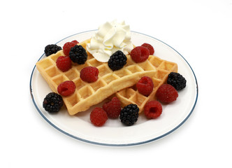  fresh belgian waffles with raspberrys, blackberries  and whipped cream on a plate isolated on white background