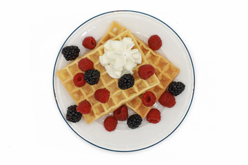  fresh belgian waffles with raspberrys, blackberries  and whipped cream on a plate isolated on white background