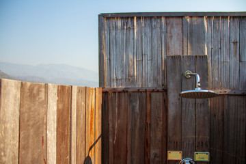 Outdoor shower with a large shower in the bathroom made from wooden wall for tourists to steep a shower after the tour.