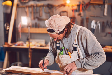 Male carpenter working on old wood in a retro vintage workshop.