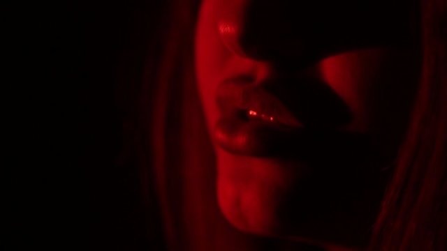Sexy female lips closeup in red light.