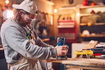 Male carpenter working on old wood in a retro vintage workshop.