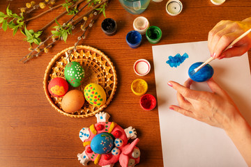 Fototapeta na wymiar The hands of the artist paint Easter eggs. Watercolor paints in cans and tubes. Handwork.
