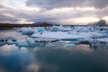 Dramatic a sunset with mirror water with blue iceberg pieces in Jokulsarlon lagoon, Iceland.