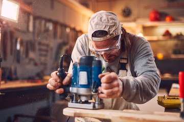 Male carpenter working on old wood in a retro vintage workshop.