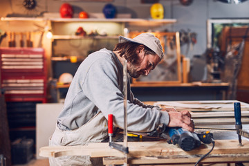Male carpenter working on old wood in a retro vintage workshop.