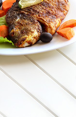 Grilled fish sea bream with vegetables on white plate. White background. Healthy diet food concept. Copy space.