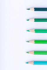 Macro photograph of several pencils of green color on a white background