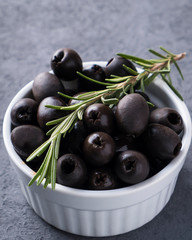 Black olives with rosemary in a bowl. Closeup