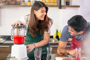 Sweet lovers making strawberry smoothie  ,healthy drink in modern pantry. happy young asian couple...