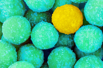 background colorful focus on yellow balls of sweets on a background of green mint candies contrast base