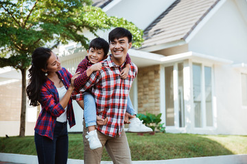 piggyride back with dad at home together. happy young family enjoy their time in their home garden