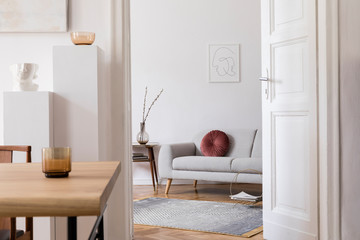 Modern scandi interior of living room with design wooden table, chairs, sofa and white stands with stylish accessories. Abstract paintings on the wall. Elegant home decor. Mock up poster frame.  © FollowTheFlow