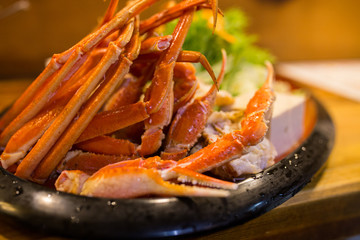 Close up king crab legs on black dish.