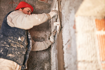 Real construction worker making a wall inside the new house.