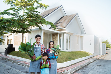 family gardening concept. asian parent with son holding a pot of plant and smiling to camera together