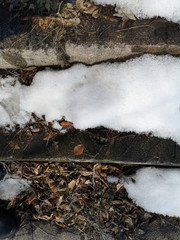 The texture of the stone staircase in the melting snow in March, in Russia closeup