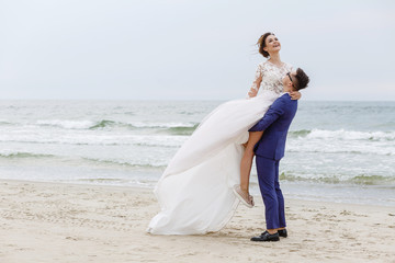 The groom whirls his bride on the beach