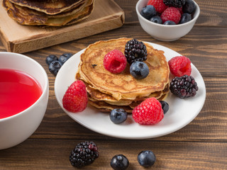 Pancakes with blueberries and strawberries on wooden background. Close Up. Soft focus.