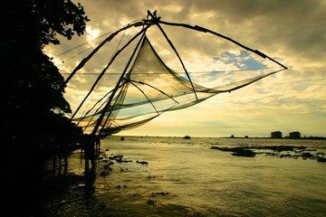 Fishing nets during sunset with sea in background at Kochi Indian