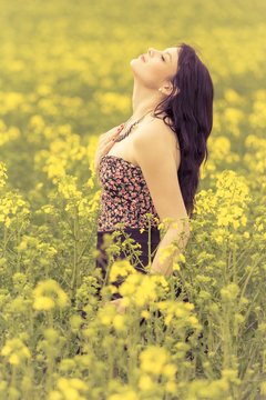 Happy beautiful woman in free summer love of wellbeing youth. Attractive young beauty girl enjoying the warm sunny sun in nature rapeseed field takes time feeling sustainability and contemplation