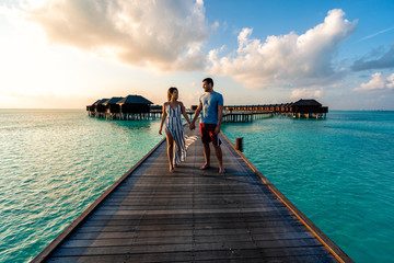 A couple enjoying a sunrise in the Maldives.   - obrazy, fototapety, plakaty