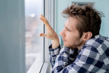 bored young man feeling sad and standing in front of the mirror  f