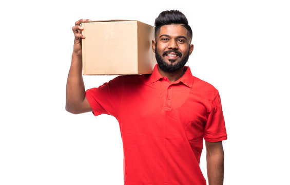 Young Smiling Indian Logistic Delivery Man In Red Uniform Holding The Box On White Background