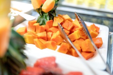 Close up of fresh and delicious diced organic mango fruit cubes on a buffet bar with serving tongs