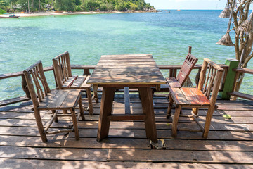 Wooden table and chairs in empty beach cafe next to sea water. Island Koh Phangan, Thailand