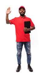 Naklejka premium Portrait a handsome young delivery man with clipboard in red cap standing with parcel post boxes isolated over white background.