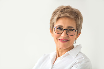 portrait of stylish aged woman with glasses and short haircut on a white background