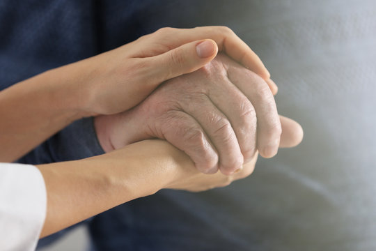 Volunteer holding hand of senior man, closeup