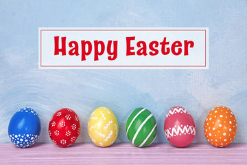 Decorated Easter eggs on table near color wall. Space for text