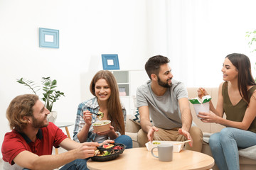 Young people having lunch together in living room. Food delivery