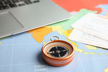 Compass, tickets and laptop on world map. Travel agency