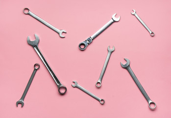 A few wrenches on a pink background.