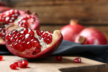 Ripe pomegranates on wooden board, closeup with space for text