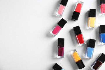 Bottles of bright nail polish on white background, top view