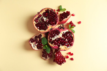Ripe pomegranates and seeds on color background, flat lay