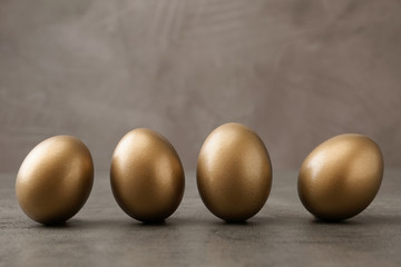 Many shiny golden eggs on grey table