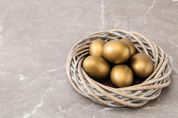 Golden eggs in nest on color background, space for text