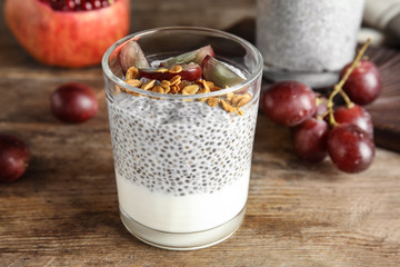 Tasty chia seed pudding with granola and ingredients on table