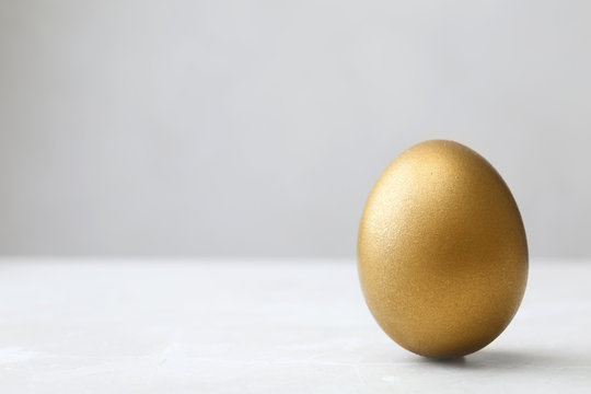 One shiny golden egg on table, space for text