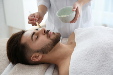Fototapeta na wymiar Cosmetologist applying mask on client's face in spa salon