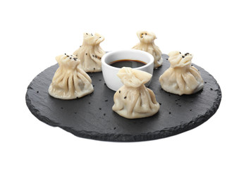 Slate plate with tasty baozi dumplings and soy sauce on white background