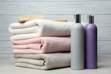 Towels with hair brush and shampoo bottles on table