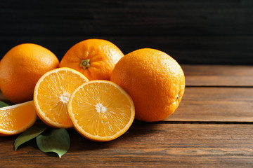 Fresh oranges with leaves on wooden table. Space for text